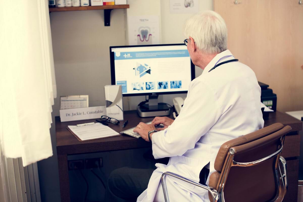 Doctor sitting at a computer desk, typing on a keyboard
