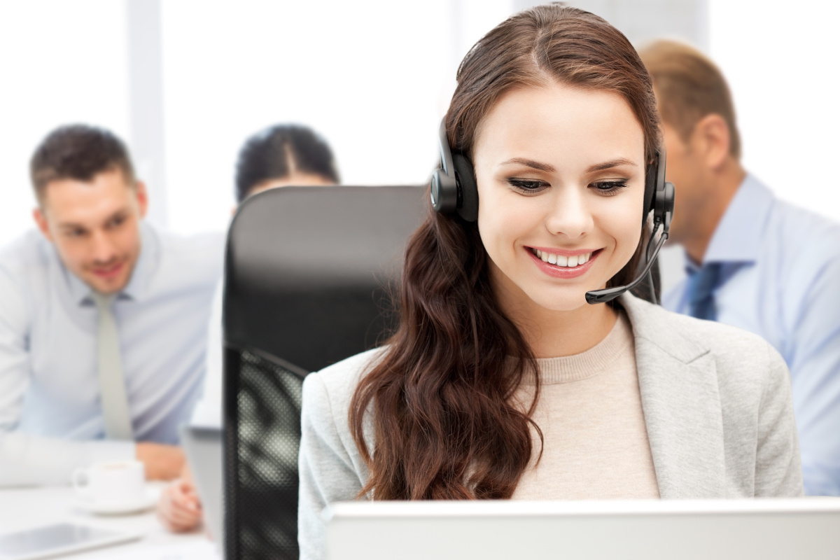 A help desk employee wearing headphones and smiling