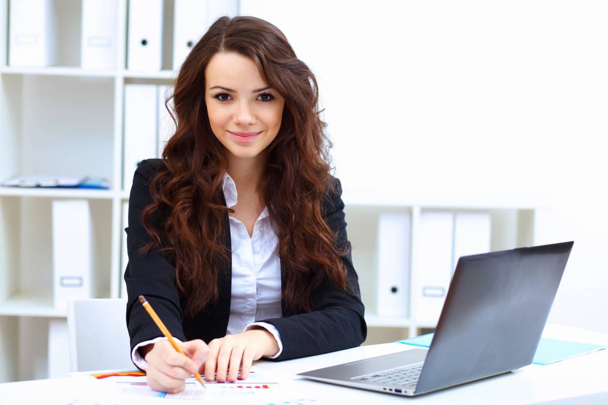 A business woman smiling while working on a laptop