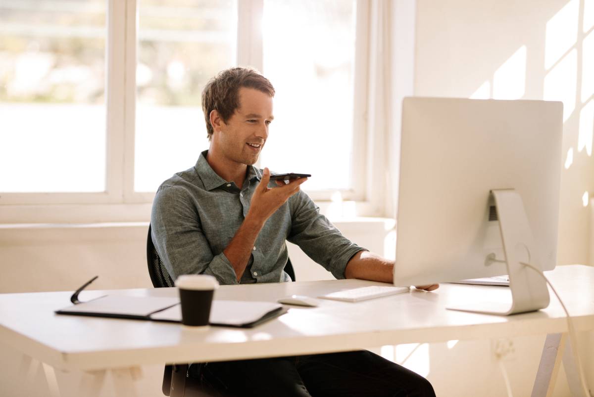 A man working from home using a computer and talking on his phone