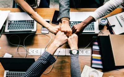 Five Students Around Table with Laptop Computers Fist Bumping