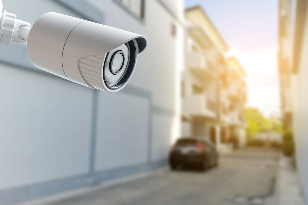 CCTV security camera monitoring street corner between homes.