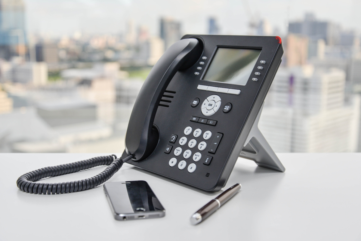 VoIP office phone on desk with cityscape in background.