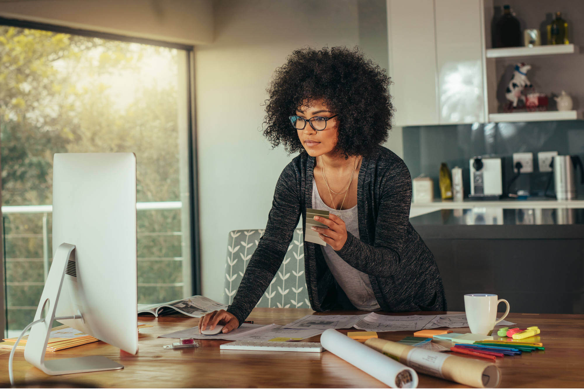 Woman working from home office leaning forward over desk towards monitor